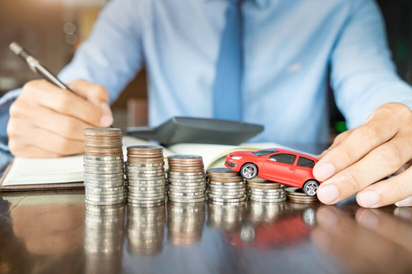 Diminishing Value Claims Person writing in a notebook while holding a toy car on a stack of coins